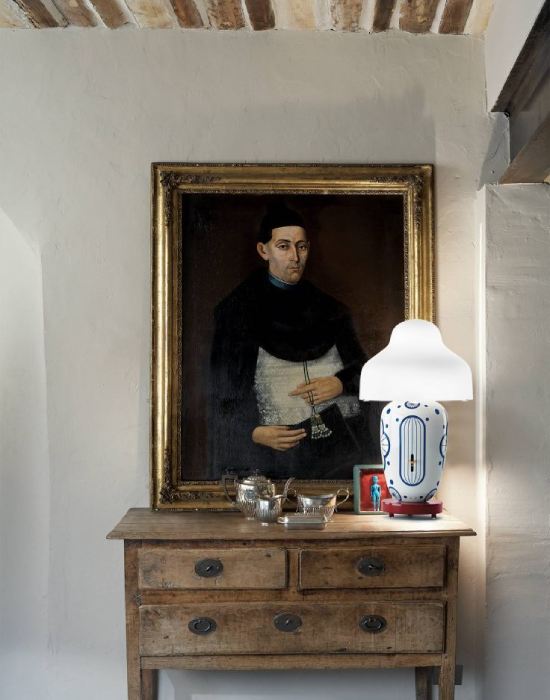 Parachilna's Chinoz table lamp, designed by Jaime Hayón, adds an exuberant touch to a rough rustic credenza with a large painted portrait atop it.
