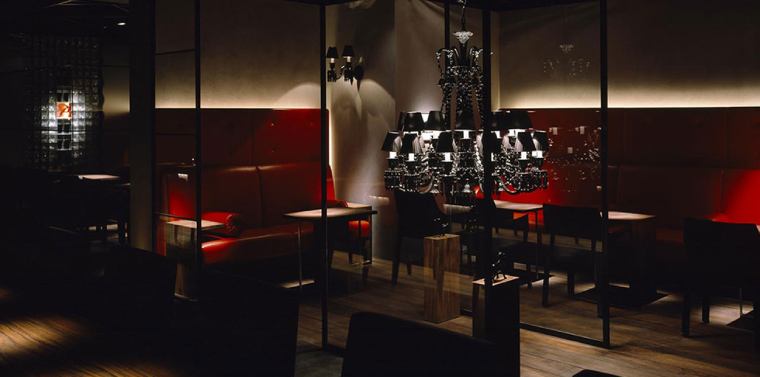 A chic upscale restaurant, dramatically illuminated by Zenith Noir wall sconces and a Zenith Noir chandelier.