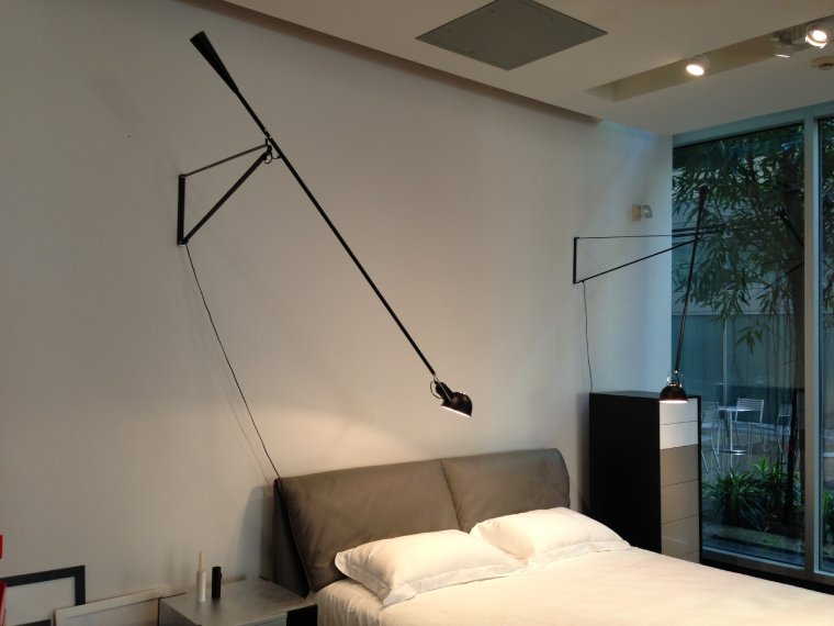 Paolo Rizzatto's 265 wall lights for FLOS hang out over the headboard of a bed.