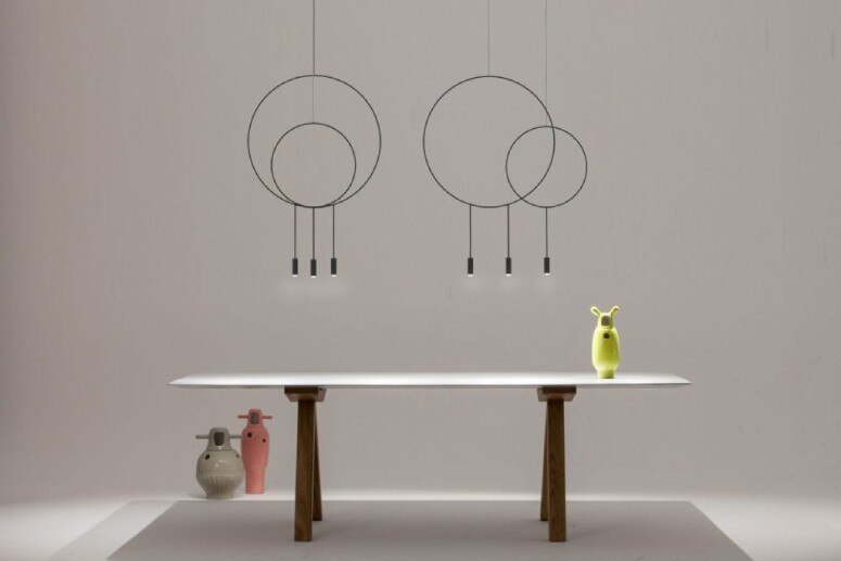 Two versions of Nahtrang Studio's Revolta pendant lights hang above a dining room table.