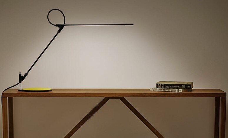 Pablo Designs' Superlight desk lamp by Peter Stathis and Matthew Boyko sits on a wooden side table.