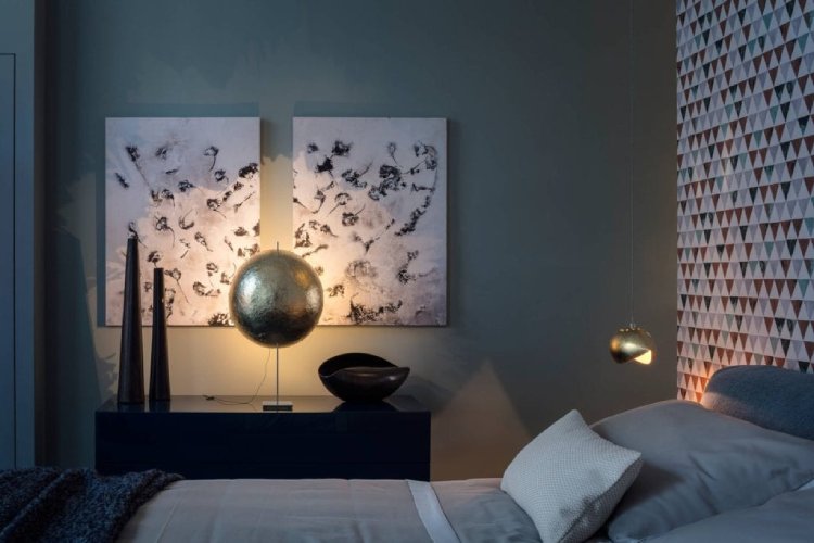 A darkened bedroom with soft, warm highlights provided bedside by PostKrisi T 40 table light and Malagola suspension light.