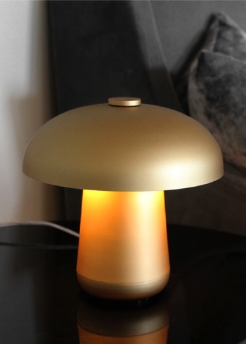 Ongo Battery table lamp from Contardi sits on an end table next to a plush sofa.