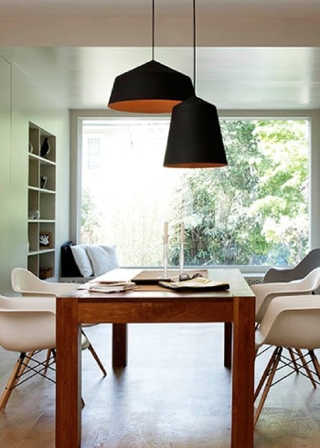 Several Circus pendant lights hang above a wooden dining table in a bright, open space.