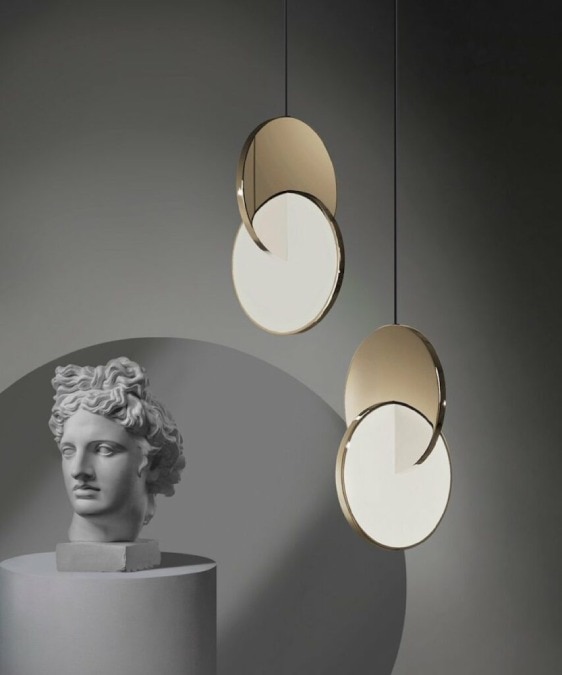 A studio photo featuring a pair of Lee Broom's EDIDA-winning Eclipse pendant lights next to a marble bust atop a plinth.