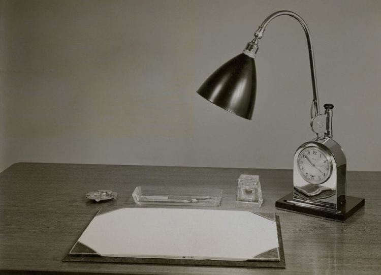 A vintage photo of a desktop featuring a BestLite illuminating the desk blotter.