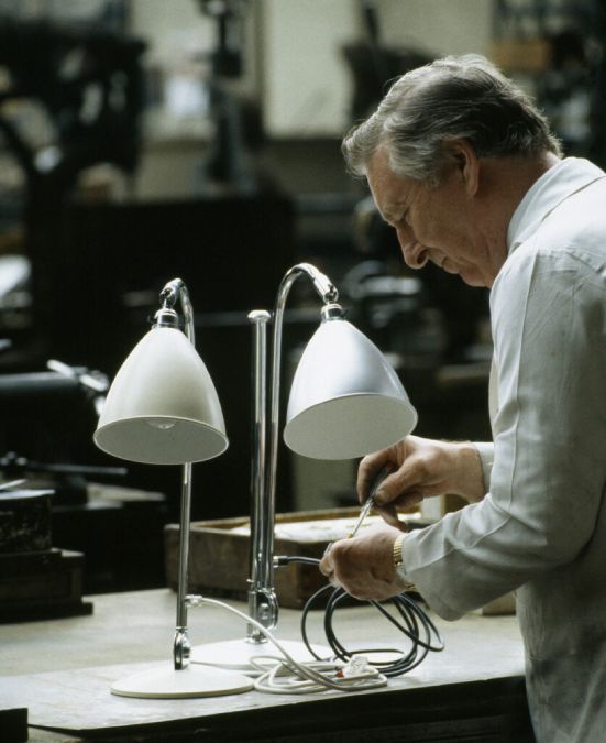 A GUBI craftsman works on a BestLite BL1 table lamp, which sits beside a BestLite BL2 table lamp.