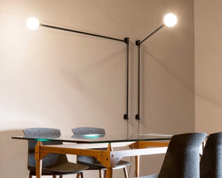 A minimalist office meeting room illuminated by Charlotte Perriand's Potence Pivotante wall lights.