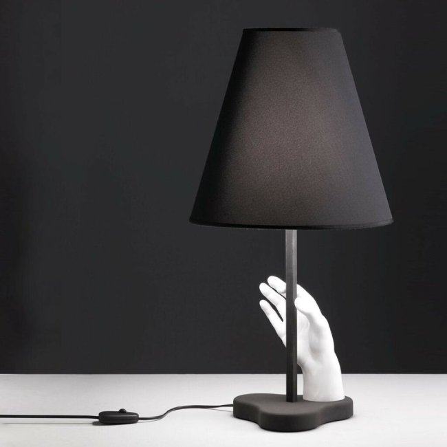 A studio image of FontanaArte's Mano table lamp, designed by Pietro Chiesa, comprised of a white marble hand holding a black metal lamp stem.