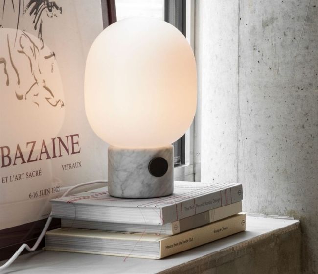 Jonas Wagell's JWDA Marble table light for Menu sits on a stack of books upon a dresser next to a bedroom window.