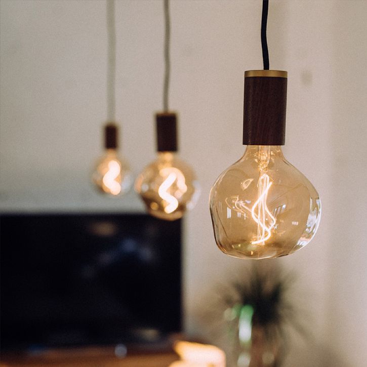Three of Tala's Voronoi II designer light bulbs hang in a den with a flat-screen television in the background
