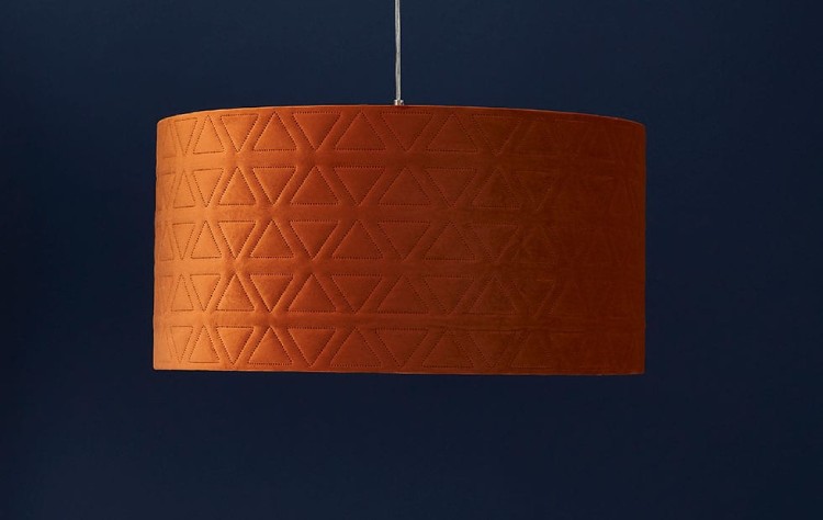 A close-up of a bespoke drum pendant light with a diffuser featuring the precise quilting of Innermost's Harrogate material in Burnt Orange Triangles.