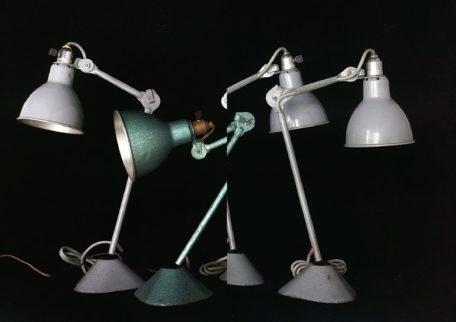 Four classic Lampe Gras table lamps on a black background.