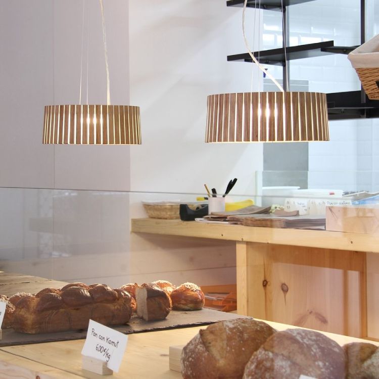 A Spanish bakery counter with bread and pasteries illuminated by Arturo Alvarez's Shio suspension lights.