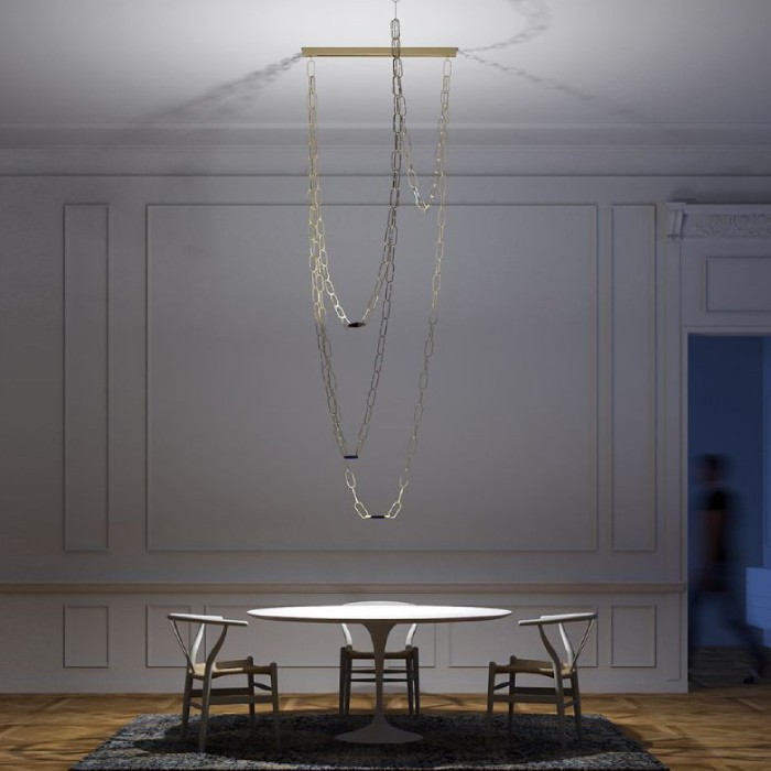 An intimate dining table in an elegant and spacious dining room is illuminated by Davide Groppi's ChainDelier. As is common in Davide Groppi's promotional images, a motion-blurred person is captured in the doorway.