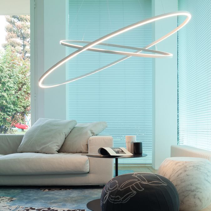 A comfortable contemporary living room with the blinds closed and Ellisse Double suspension light hanging above the end table.