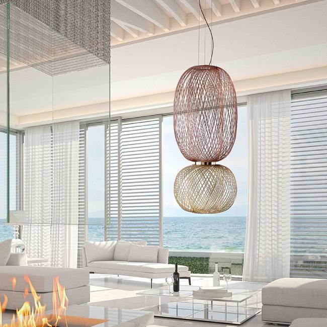 A bright and open residential space with both a gas-flame fire pit and an ocean view, with Anwar T 30 suspension light's intricate form foregrounded.