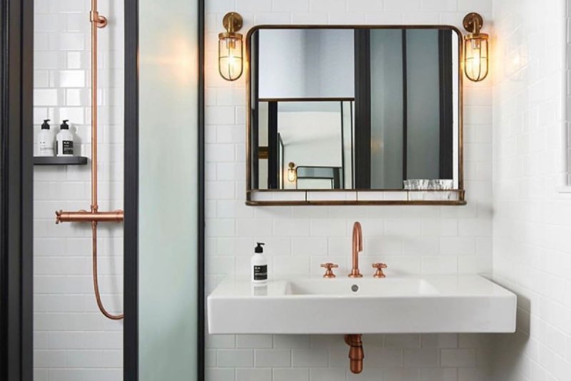 A pair of Ship Well wall lights hang to either side of a vanity mirror in a minimalist modern bathroom./