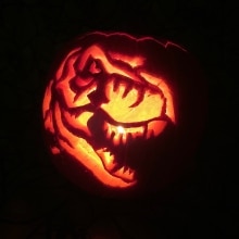 A jack-o'-lantern with a T-rex head carved into it.