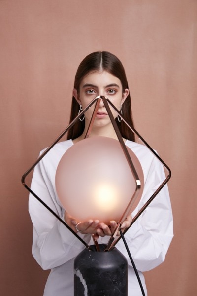 A model holds the acid-etched glass sphere of Jack O'Lantern Large table lamp, designed for Brokis by creative director Lucie Koldova.