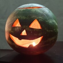 A jack-o'-melon on a side table, grinning redly.