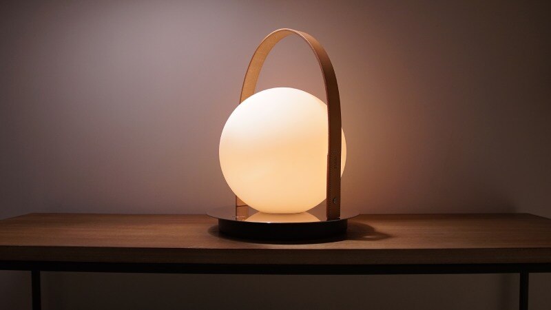 Bola Lantern portable table light from Pablo sits on a wooden sidetable.