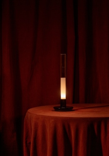 Sylvestrina portable table lamp sits on a table on a red-robed set.