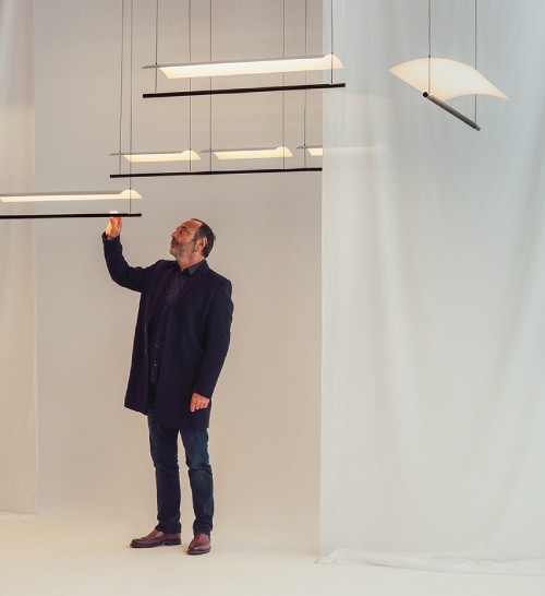 Lighting designer Antoni Arola interacts with one of his Lamina linear suspension lights.