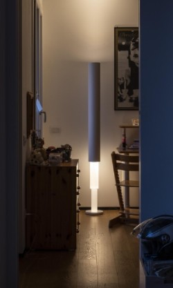 Palomar floor lamp, designed by Ludovica and Roberto Palomba for Foscarini, shines through a doorway in a contemporary apartment.