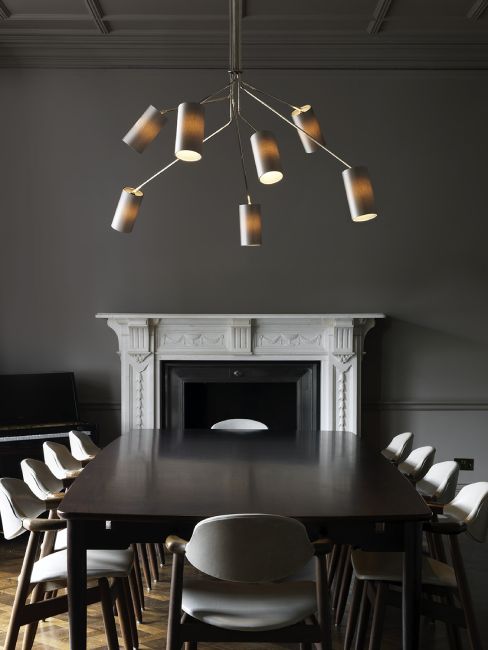 The multi-headed Array Cotton Suspension chandelier illuminates a staid and dignified dining table with a fireplace at one end.