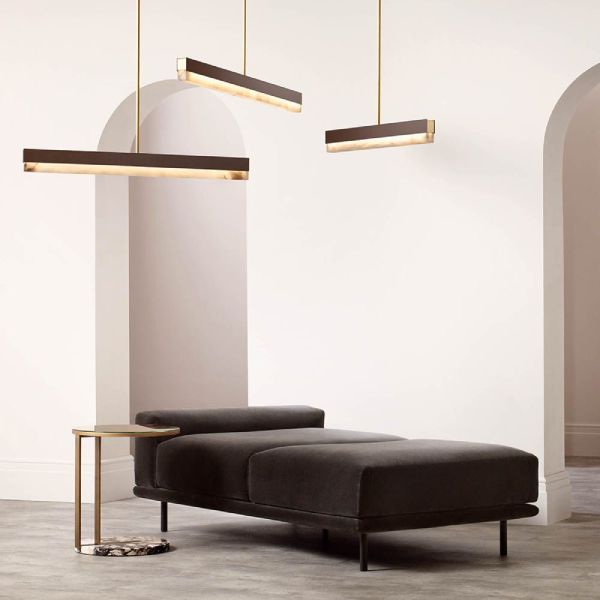 A cluster of Artés linear suspension lights hangs above a rich velvet divan and brass side-table.