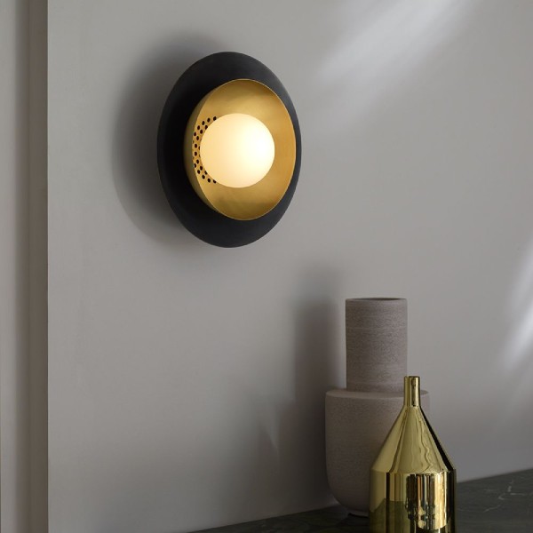 Carapace wall sconce from CTO Lighting illuminating a sideboard with objets d'art on it.