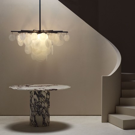 Nimbus chandelier from CTO Lighting over a marbled black and white table at the base of a curving staircase.