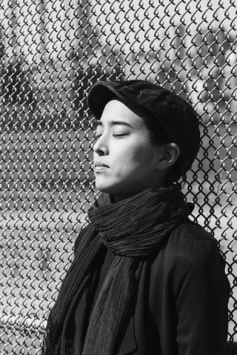 Japanese-born New York lighting designer Nao Tamura leans against a chain link fence