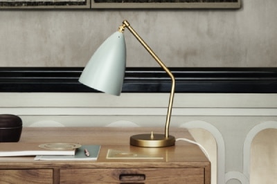 A Gräshoppa table lamp sits upon a wooden desk.