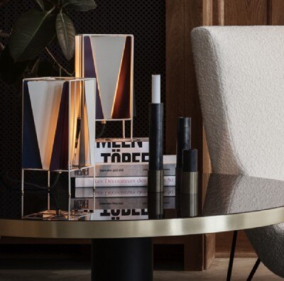 A pair of B-R table lamps sit with books on a table beside a lush modernist chair.