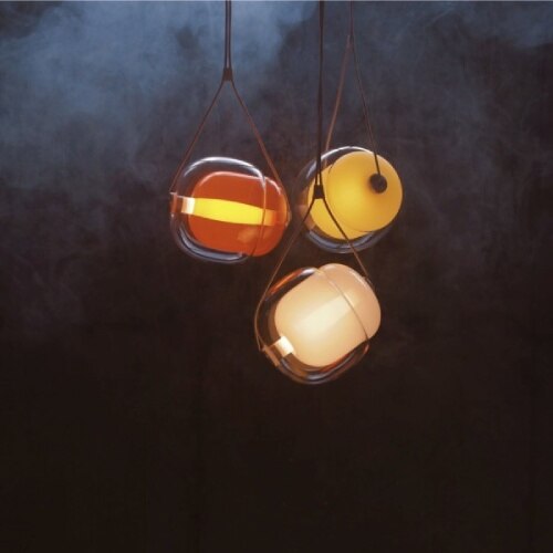 A trio of Capsula pendants, designed by Lucie Koldova, in various colours illuminate a darkened set.