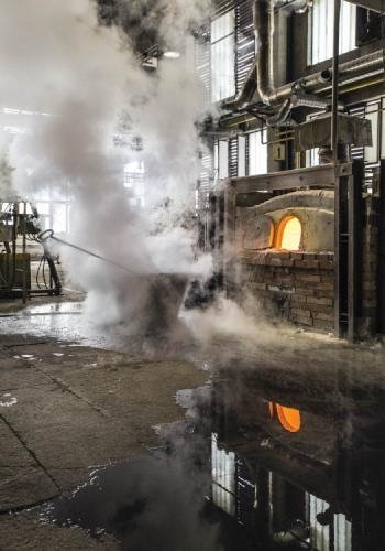 A wide shot of an oven at Janstejn Glassworks. A great cloud of water vapour rises next to it.