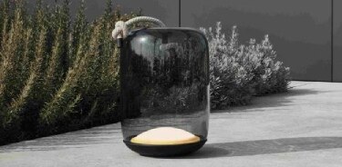 Knot Battery portable outdoor table lamp by Chiaramonte Marin, illuminated and sitting on a concrete patio.