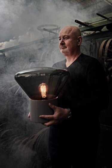 Brokis founder Jan Rabell poses with Muffins table lamp at Janstejn Glassworks in an atmospheric photo.