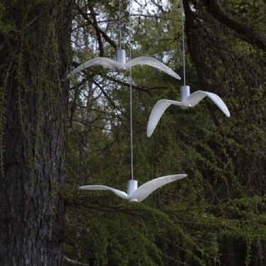 A cluster of white Night Birds pendants in a wooded area. Photo by Jan Voharčík