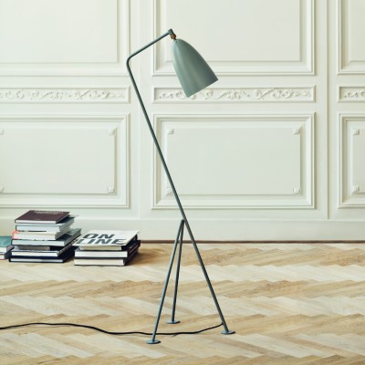 Gubi's Gräshoppa reading light, designed by Greta Magnussen-Grossman, sits near a stack of books.