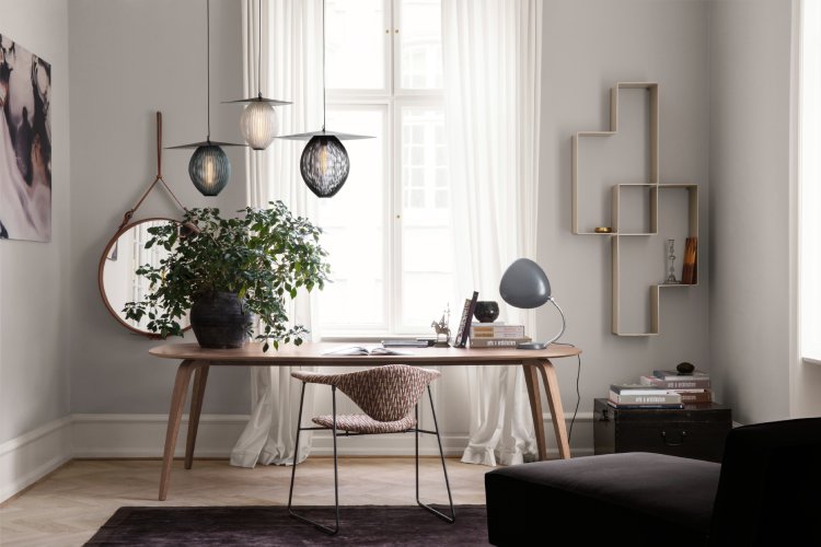 A trio of Satellite suspension lights from Gubi form a cluster over a simple desk, atop which sits a Cobra table lamp.