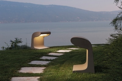 Two concrete Borne Beton Grande outdoor floor lights from Nemo, designed by Le Corbusier, illuminate a path overlooking a body of water.