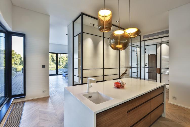 A cluster of Chiaramonte Marin's Knot suspension lights hang over a kitchen island in a warm contemporary home.