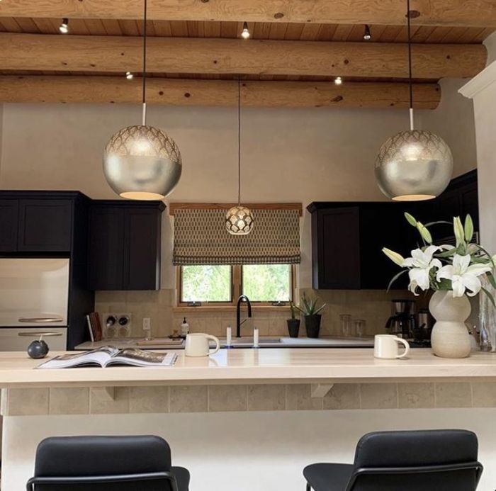 A pair of Nur pendants from Dounia Home hang over a kitchen counter.