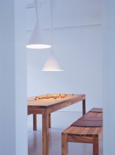 Karman's Diabolo pendant lights hang over a wooden table in a dining room with spare Scandinavian decor.