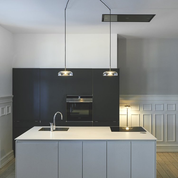 A pair of Nuura's Blossi 1 pendants, designed by Sofie Refer, illuminate a minimalist contemporary kitchen.