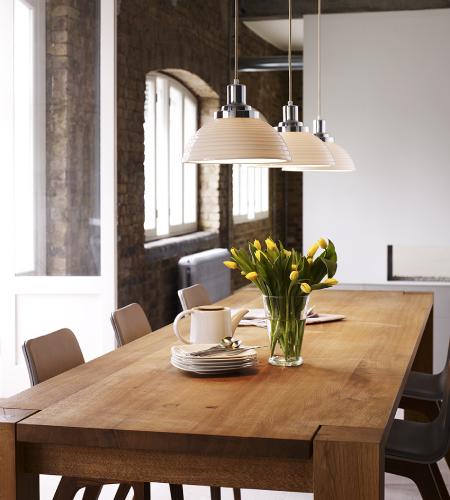 A linear cluster of Cosmo suspension lights over a wooden dining table in a large open space.