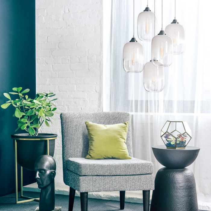 A cluster of Haze pendants from Niche hang over a chair and side table in a contemporary living room.